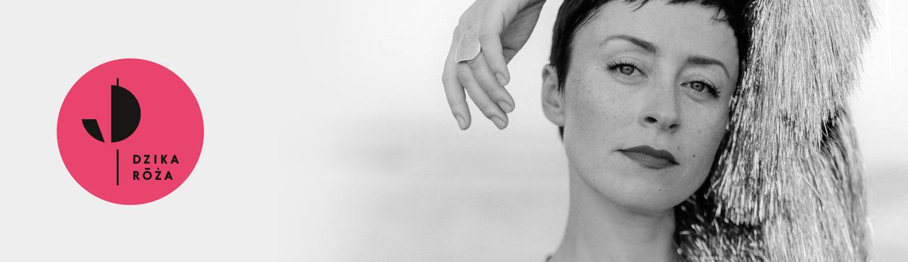 Czarno-biały portret. Krótkowłosa brunetka pozuje trzymając lewą rękę na głowie.